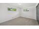 A sunlit bedroom with plush carpeting and two windows showcasing the outdoor greenery at 169 Yates St, Denver, CO 80219