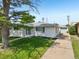 Inviting white brick home with lush green lawn, mature trees, and long driveway leading to the detached garage at 169 Yates St, Denver, CO 80219
