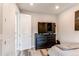 Light bedroom features a dark dresser with a television and access to the hallway at 21302 E Radcliff Pl, Aurora, CO 80015
