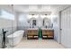 Bright bathroom with a soaking tub, dual sink vanities, wood cabinets, and stylish mirrors at 21658 E Tallkid Ave, Parker, CO 80138