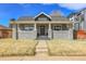 Charming gray brick home with a welcoming front porch and well-manicured lawn under a bright blue sky at 2827 Bellaire St, Denver, CO 80207