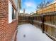 Fenced backyard featuring a brick exterior and patches of snow at 9976 Appletree Pl, Thornton, CO 80260