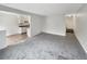 An empty living room featuring neutral carpet, paint, and entryway to kitchen and stairs at 9976 Appletree Pl, Thornton, CO 80260