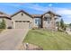 Inviting home exterior with a lush lawn, long driveway, and stone accents, showcasing a well-maintained property at 360 Basilwood Way, Highlands Ranch, CO 80126