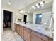 Bright bathroom with a double sink vanity, marble countertops, and direct access to a walk-in closet at 17955 E 107Th Pl, Commerce City, CO 80022