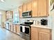 Well-lit kitchen featuring stainless steel appliances, light wood cabinetry and light countertops at 17955 E 107Th Pl, Commerce City, CO 80022