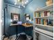 Stylish office with blue walls features a treadmill desk, shelving, and unique lighting fixture at 756 Ranchhand Dr, Berthoud, CO 80513