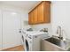 Laundry room with washer, dryer, utility sink, overhead cabinets, and wood-look floors at 3866 S King St, Denver, CO 80236