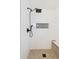 Modern shower with a black shower head, white tiled walls, and a built-in bench with gray flooring at 3866 S King St, Denver, CO 80236