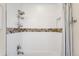 Clean, tiled shower with a decorative accent stripe and chrome fixtures at 2600 S Sherman St, Denver, CO 80210
