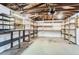 Unfinished basement area with exposed ceiling beams, cement flooring, and a shelving unit at 8511 Essex Dr, Denver, CO 80229