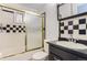Cozy bathroom with checkerboard tile accents, vanity, mirror, and shower with a sliding door at 8511 Essex Dr, Denver, CO 80229