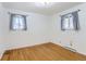 Well-lit bedroom featuring natural hardwood floors, white walls, and large windows with patterned curtains at 8511 Essex Dr, Denver, CO 80229