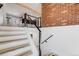 Modern staircase with wood treads, metal railings, and a striking brick accent wall for a stylish transition at 2764 S Reading Ct, Denver, CO 80231
