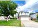 Suburban two-story home with a well-kept lawn, complemented by a two-car garage and mature tree at 12566 Dexter St, Thornton, CO 80241