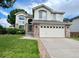 Charming two-story home with brick accents, a two-car garage, and a lush green lawn under a cloudy sky at 12566 Dexter St, Thornton, CO 80241