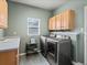Laundry room with washer, dryer, sink, storage cabinets, and a window, offering a complete laundry solution at 8346 Vivian St, Arvada, CO 80005