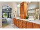 Bathroom with double sinks, wood cabinets, and an arched entry to the main bedroom at 6776 Salvia Ct, Arvada, CO 80007