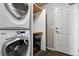Convenient laundry room equipped with a stacked washer/dryer, storage shelves, and practical tile flooring at 6776 Salvia Ct, Arvada, CO 80007