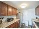 Kitchen featuring stainless steel refrigerator, granite counters, tile backsplash, and brown cabinets at 3331 S Monaco Pkwy # D, Denver, CO 80222