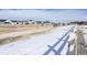 Snow covered community pathway with new homes and white fence at 7033 S Waterloo Way, Aurora, CO 80016
