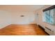 Open living room showcasing pristine hardwood floors, white walls, a large window, and a heating unit for comfortable living at 558 N Washington St # 103, Denver, CO 80203