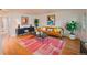 A stylish living room with hardwood floors, modern decor, a cozy tan leather sofa, and brightly colored artwork at 558 N Washington St # 103, Denver, CO 80203