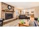 Cozy living room featuring a brick fireplace, wood floors, and an open layout into the kitchen at 7926 S Corona Ct, Centennial, CO 80122