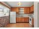 Traditional kitchen with wood cabinets, vintage white appliances and brick accent wall at 2683 E 90Th Pl, Thornton, CO 80229