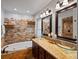 Luxurious bathroom featuring double sinks, granite countertops, an elegant stone accent wall, and a jetted tub at 5884 S Hanover Way, Greenwood Village, CO 80111