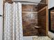 Bathroom with neutral colors featuring a shower with bronze hardware and intricate brown tiling and a white patterned shower curtain at 5884 S Hanover Way, Greenwood Village, CO 80111