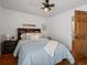 Cozy bedroom with a patterned comforter, wood floors, a ceiling fan, bedside table, and an open doorway at 5884 S Hanover Way, Greenwood Village, CO 80111