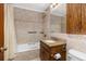 Hall bath features a shower-tub combination, tile surround, and a wooden vanity with a granite countertop at 26063 Morris Ave, Conifer, CO 80433
