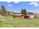 Charming exterior view with a detached garage, shed, and lush green lawn in a serene setting at 26063 Morris Ave, Conifer, CO 80433