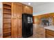 Kitchen displays a large pantry and black refrigerator adjacent to a living room with a stone fireplace at 26063 Morris Ave, Conifer, CO 80433