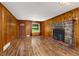 Cozy living room featuring wood paneling, a classic stone fireplace, and hardwood-style flooring at 26063 Morris Ave, Conifer, CO 80433