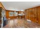 Spacious living room features wood paneling, flooring, a stone fireplace, and views into the kitchen at 26063 Morris Ave, Conifer, CO 80433