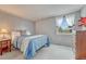 Cozy bedroom featuring a comfortable blue quilted bed, soft carpet and bright natural light from the window at 7100 S Hudson Cir, Centennial, CO 80122