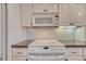 Kitchen features white appliances, white cabinetry, and tile backsplash at 7100 S Hudson Cir, Centennial, CO 80122