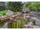 Picturesque waterfall flowing into a pond surrounded by rocks and lush greenery at 7100 S Hudson Cir, Centennial, CO 80122