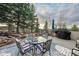 Outdoor patio area with wrought iron furniture, a glass-topped table, and a grill, surrounded by trees at 814 Neville Ln, Golden, CO 80401