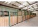 Inside the horse barn, see the stalls and a long open alley way at 5351 Tall Horse Trl, Sedalia, CO 80135