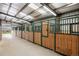 Brightly lit horse barn interior featuring wood and metal stalls at 5351 Tall Horse Trl, Sedalia, CO 80135