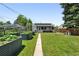 Backyard view highlighting metal garden beds, a patio, and a well-maintained lawn at 1240 Ulster St, Denver, CO 80220