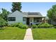 Charming home with a well-manicured front yard, complemented by lush greenery and solar panels at 1240 Ulster St, Denver, CO 80220