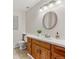 Bathroom featuring a wooden vanity, sink, toilet, and round mirror at 3311 E Euclid Ave, Centennial, CO 80121