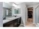 Bright bathroom featuring a double vanity, large mirror, and glass enclosed shower with a walk-in closet at 25046 E Bayaud Pl, Aurora, CO 80018