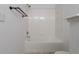 Bathroom with a white tiled shower and bathtub with black fixtures and tan vinyl flooring at 4451 S Ammons St # 2-204, Littleton, CO 80123