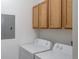 Bright laundry room with side-by-side washer and dryer and wood cabinets at 4451 S Ammons St # 2-204, Littleton, CO 80123
