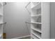 A walk-in closet with multiple built-in white shelving units and carpet flooring at 4451 S Ammons St # 2-204, Littleton, CO 80123
